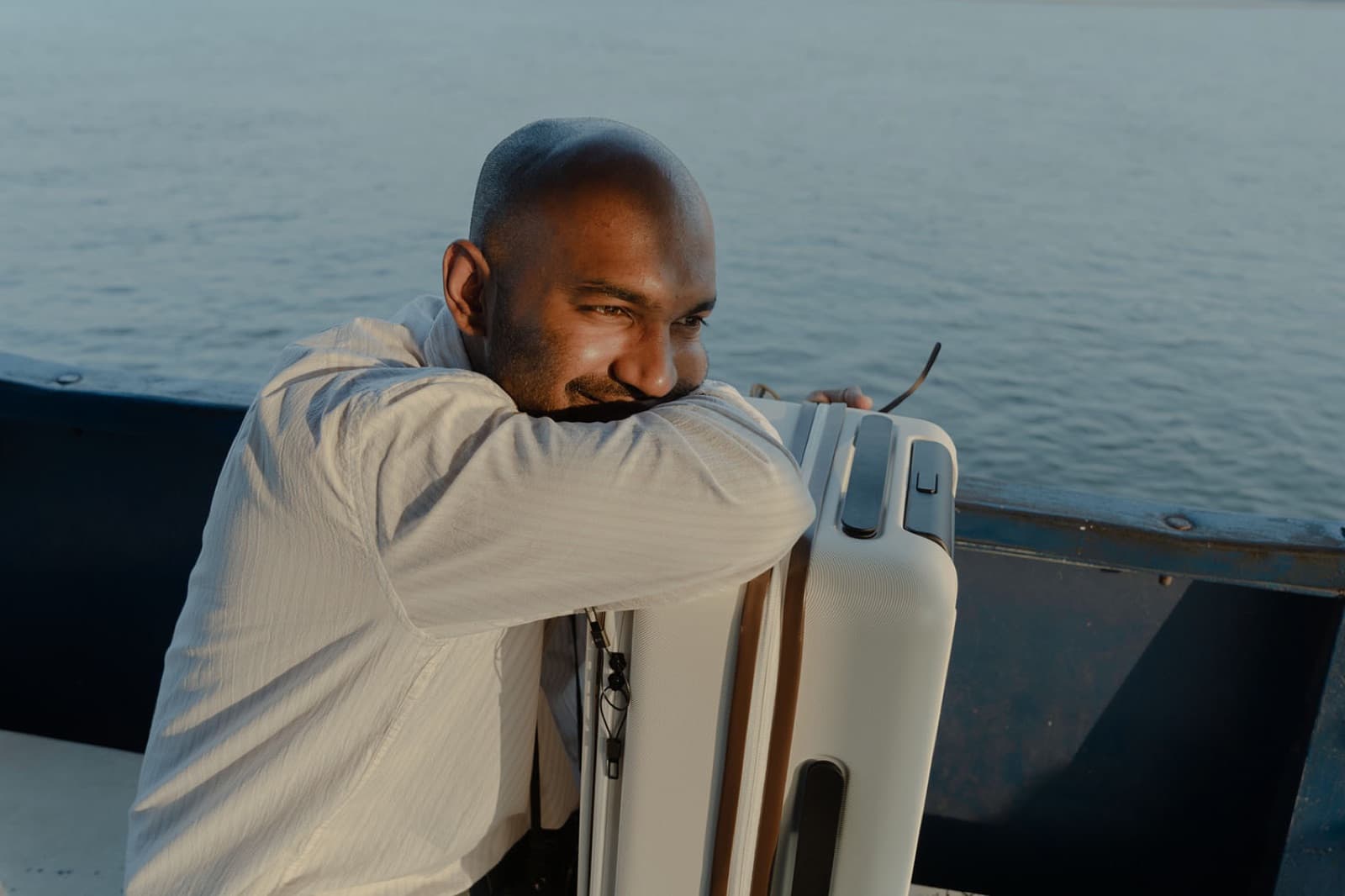 Hombre con equipaje contemplando el mar al atardecer